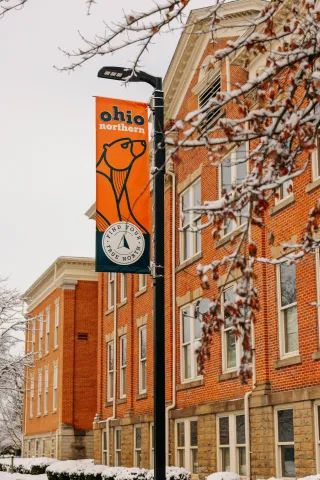 Photo of ONU in the first snow of the year.  Buildings in the background and Ohio Northern flag